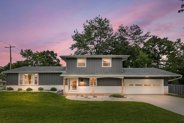 view of front of house featuring covered porch, a yard, and a garage