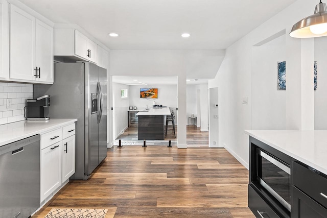 kitchen with decorative backsplash, appliances with stainless steel finishes, dark hardwood / wood-style floors, and white cabinetry