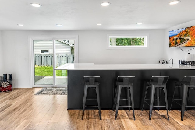 kitchen with a breakfast bar area, kitchen peninsula, a wealth of natural light, and light wood-type flooring