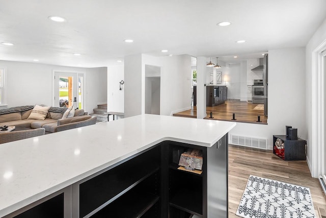 kitchen with stove, wall chimney exhaust hood, and light hardwood / wood-style floors