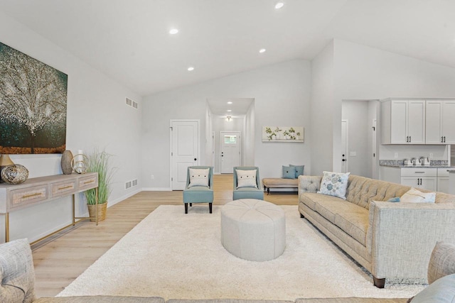 living room featuring high vaulted ceiling and light wood-type flooring