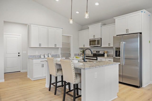 kitchen with an island with sink, white cabinets, and stainless steel appliances