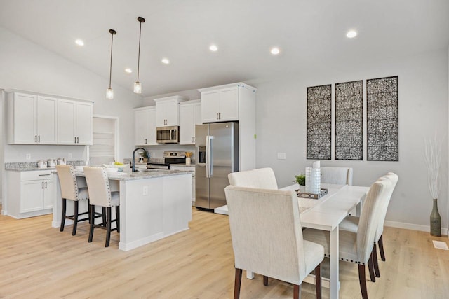 dining space with light hardwood / wood-style floors and lofted ceiling