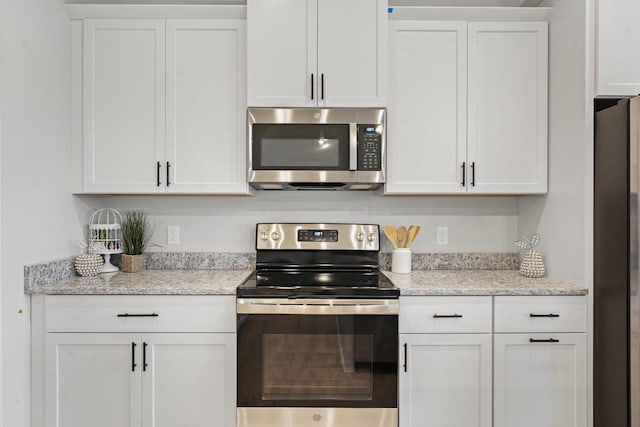 kitchen with white cabinets, stainless steel appliances, and light stone counters