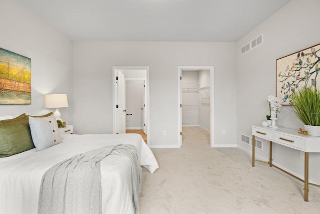 bedroom featuring light carpet, a walk in closet, and a closet