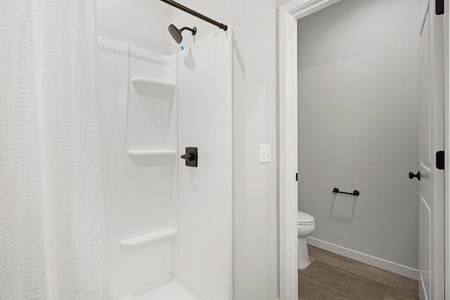 bathroom featuring toilet, hardwood / wood-style floors, and a shower with curtain