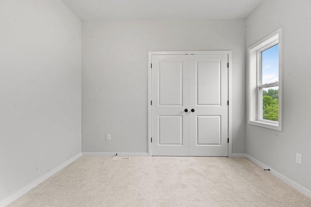 unfurnished bedroom featuring light carpet and a closet