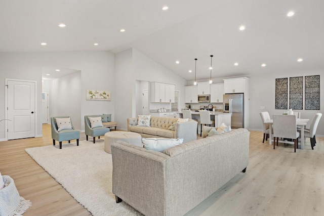 living room featuring high vaulted ceiling and light wood-type flooring