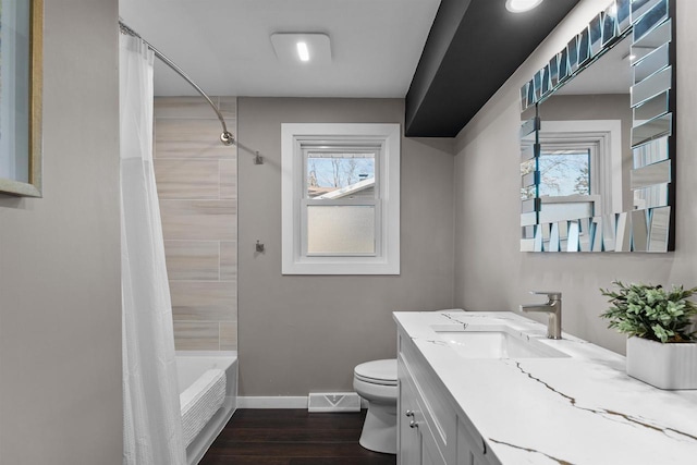 full bathroom with a wealth of natural light, shower / bathtub combination with curtain, toilet, vanity, and hardwood / wood-style flooring