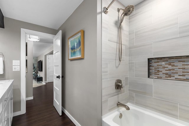 bathroom with hardwood / wood-style floors, vanity, and tiled shower / bath