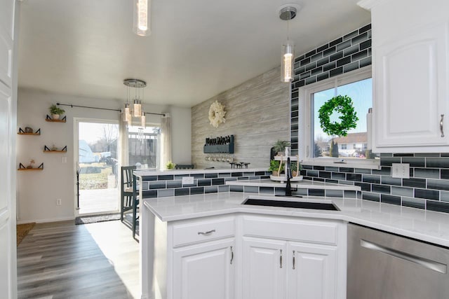 kitchen with stainless steel dishwasher, sink, white cabinets, and hanging light fixtures