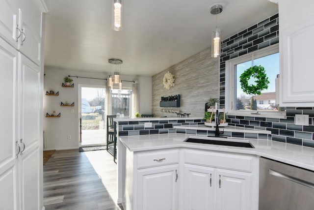 kitchen featuring dishwasher, backsplash, sink, hanging light fixtures, and white cabinetry