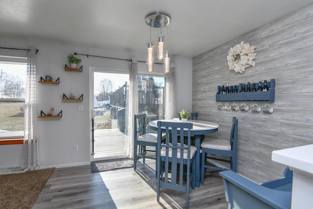 dining room with wood walls, an inviting chandelier, and hardwood / wood-style flooring