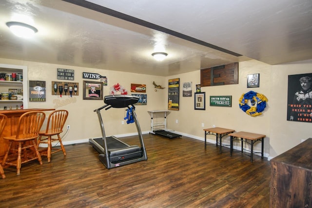 workout area with dark wood-type flooring and bar