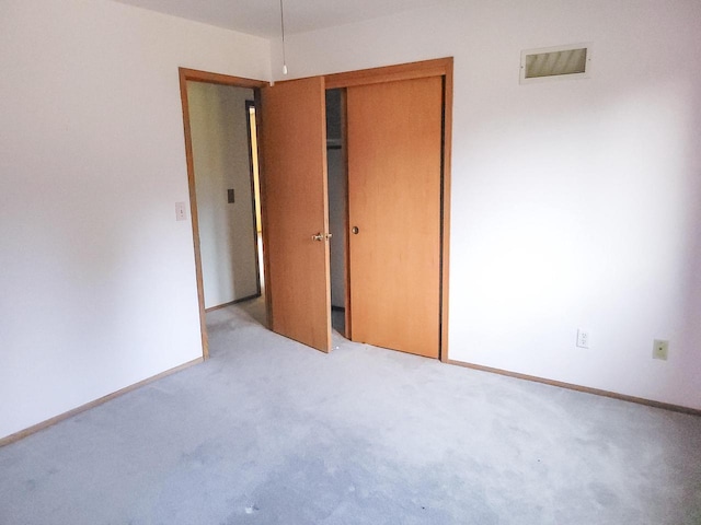 unfurnished bedroom with light colored carpet and a closet