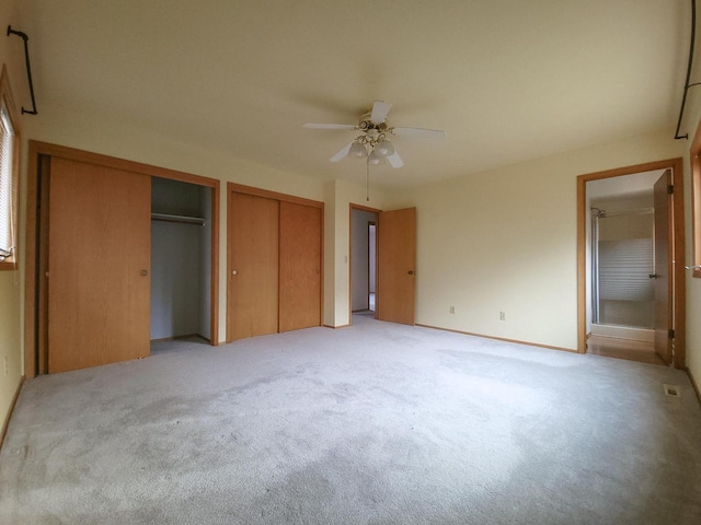 unfurnished bedroom with multiple closets, ceiling fan, and light carpet