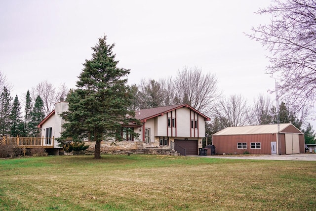 view of front of home with a front yard, a garage, an outdoor structure, and a wooden deck