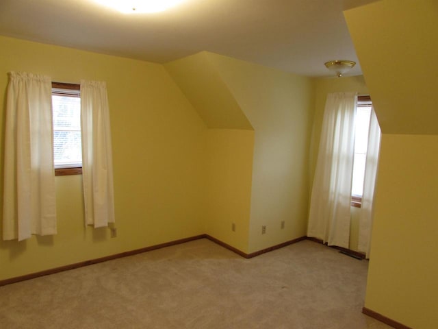 additional living space featuring light carpet and vaulted ceiling