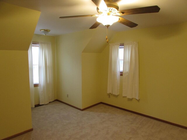 additional living space featuring light carpet, vaulted ceiling, ceiling fan, and a healthy amount of sunlight