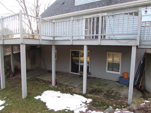 snow covered back of property with a wooden deck