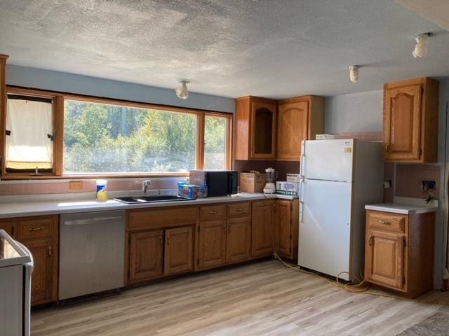 kitchen with sink, stainless steel dishwasher, white refrigerator, light wood-type flooring, and range