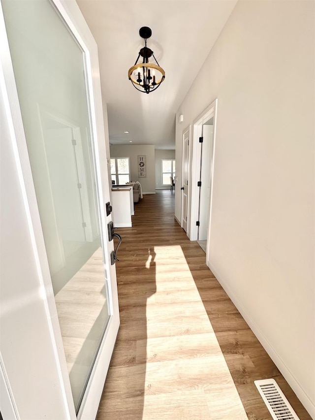 hallway featuring hardwood / wood-style floors and a notable chandelier