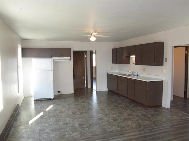 kitchen featuring dark brown cabinetry, ceiling fan, sink, and white fridge