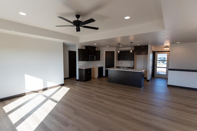 interior space with a tray ceiling, ceiling fan, dark wood-type flooring, and sink