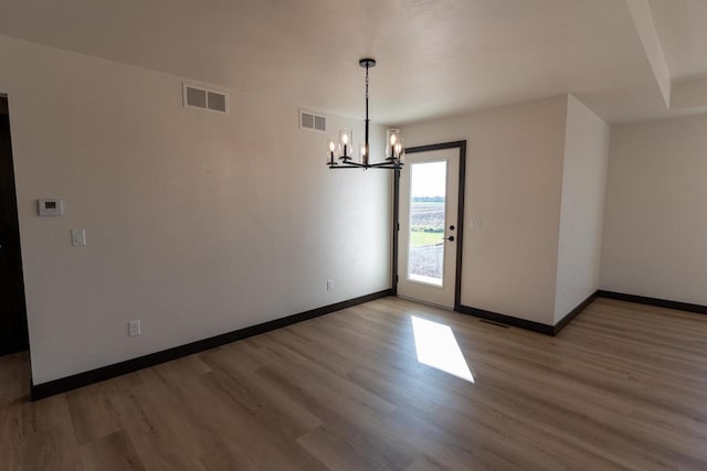 spare room featuring wood-type flooring and a notable chandelier