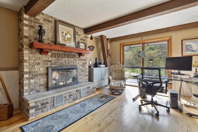 office featuring a fireplace, light hardwood / wood-style floors, and a textured ceiling