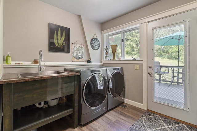 laundry room with wood-type flooring, washer and clothes dryer, and sink