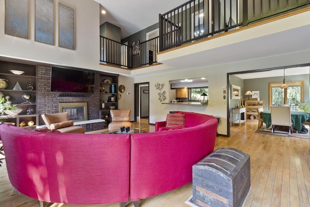 living room featuring hardwood / wood-style flooring, built in shelves, a fireplace, and a high ceiling