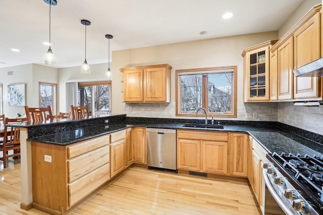 kitchen with sink, dark stone countertops, hanging light fixtures, stainless steel appliances, and kitchen peninsula