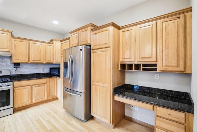 kitchen featuring appliances with stainless steel finishes, built in desk, light brown cabinets, and dark stone counters