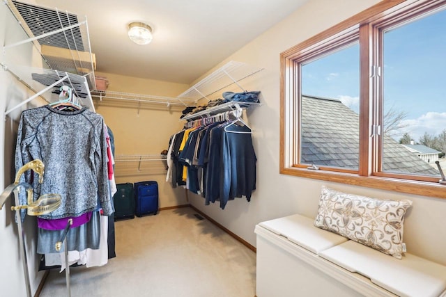 walk in closet with light carpet