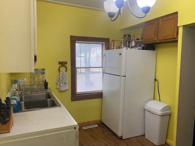 kitchen featuring dark hardwood / wood-style floors, white refrigerator, sink, and an inviting chandelier