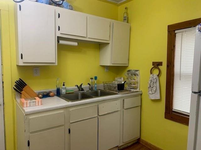 kitchen featuring white cabinetry, sink, and white fridge