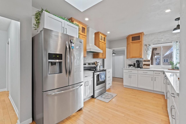 kitchen with white cabinets, appliances with stainless steel finishes, tasteful backsplash, light hardwood / wood-style floors, and custom range hood