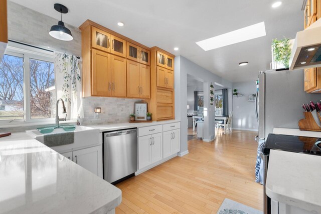 kitchen with dishwasher, stove, a skylight, decorative light fixtures, and white cabinetry