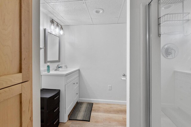 bathroom featuring a paneled ceiling, vanity, wood-type flooring, and walk in shower