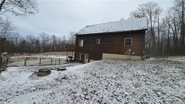 snow covered back of property featuring a wooden deck and central air condition unit