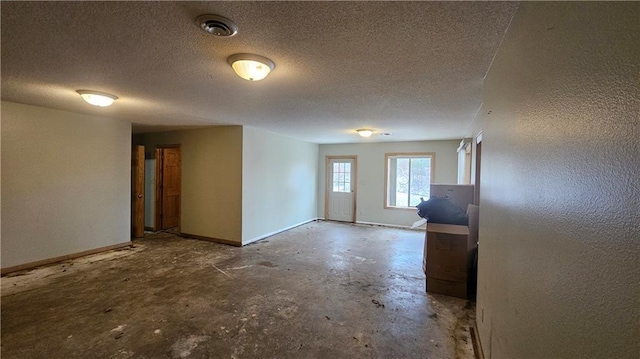 empty room featuring a textured ceiling and concrete floors