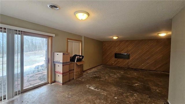 basement featuring wood walls and a textured ceiling