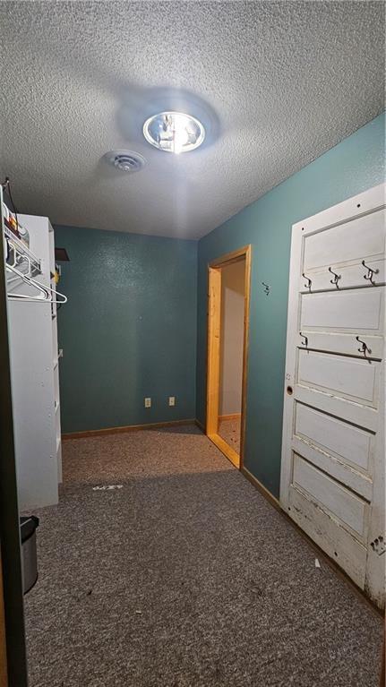 unfurnished bedroom featuring dark carpet and a textured ceiling