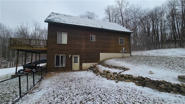 snow covered rear of property featuring a deck