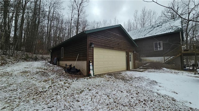 view of snow covered exterior with a garage and an outbuilding