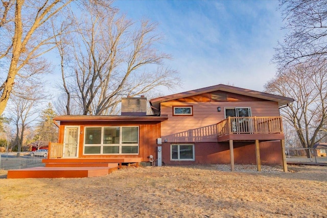 back of property with a deck and a lawn