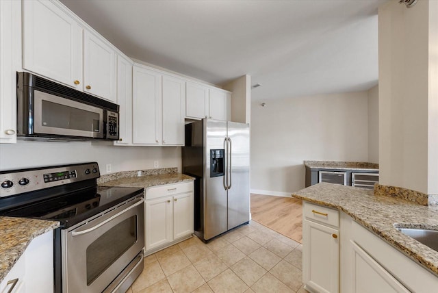 kitchen featuring light tile patterned floors, light stone countertops, white cabinetry, and appliances with stainless steel finishes