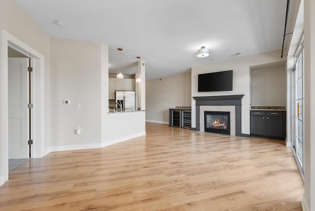 unfurnished living room featuring light hardwood / wood-style floors and a tiled fireplace