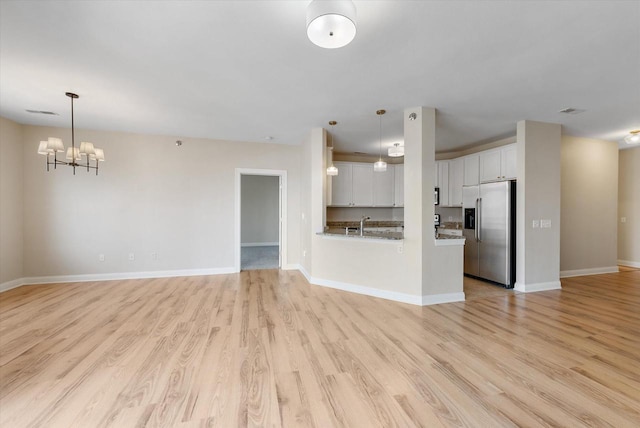 unfurnished living room with light hardwood / wood-style flooring and an inviting chandelier